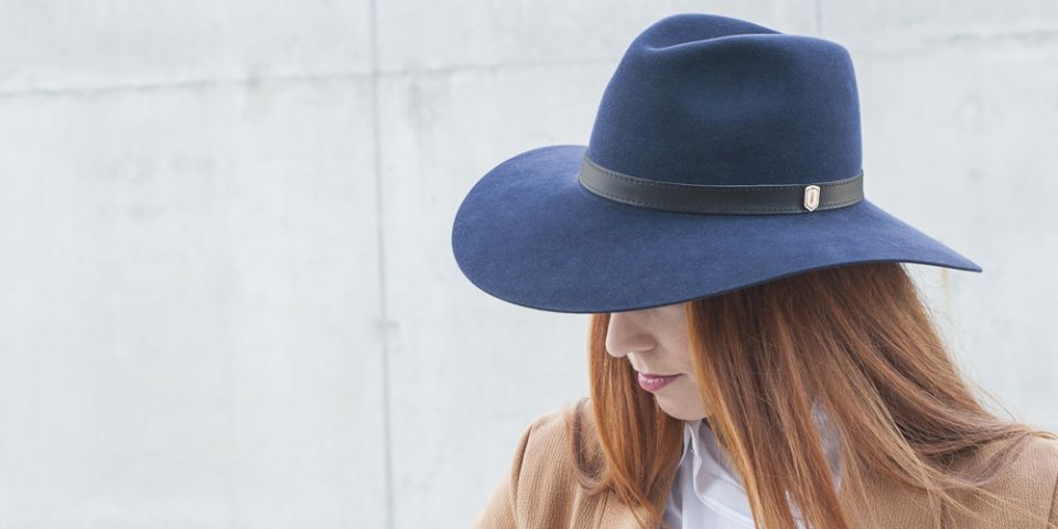 BeWooden - A woman with red hair wearing dark blue hat, brown coat and white shirt.