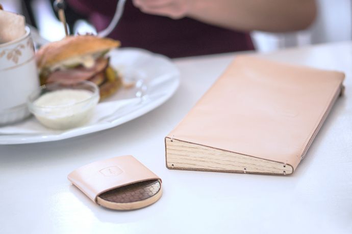 The leather Lux Clutch bag and wooden mirror Liti laid in a restaurant on the table