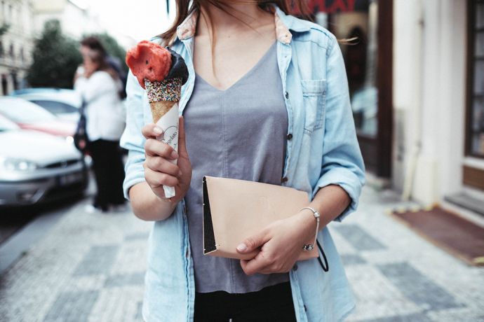 A woman in a blue shirt holds an ice cream and the leather Vespa Clutch bag with wooden detailing