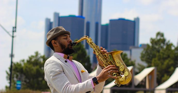 The musician Saxappeal playing saxophone wearing a hat and the Bellis wooden bow tie