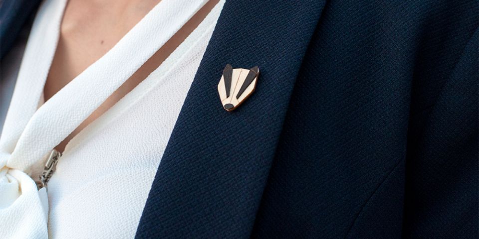 BeWooden - A woman in a jacket with the wooden brooch Badger Brooch