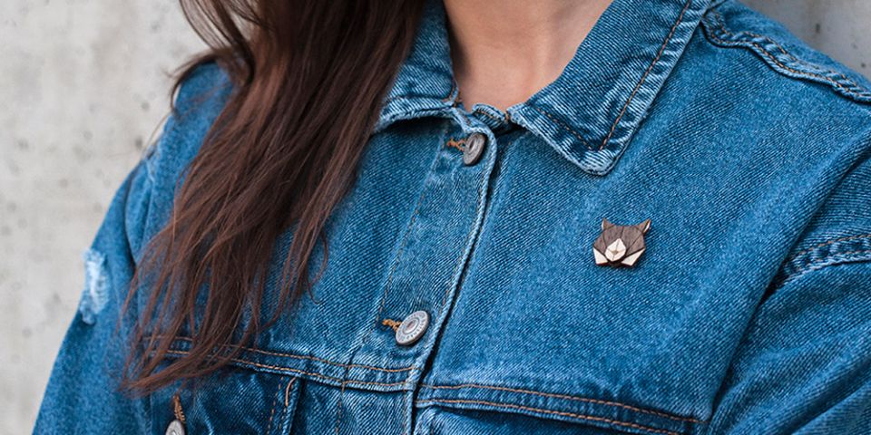 A woman in jeans jacket with the wooden brooch Lynx Brooch