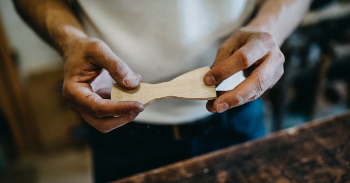 artisan from the workshop with a wooden bow tie in his hand